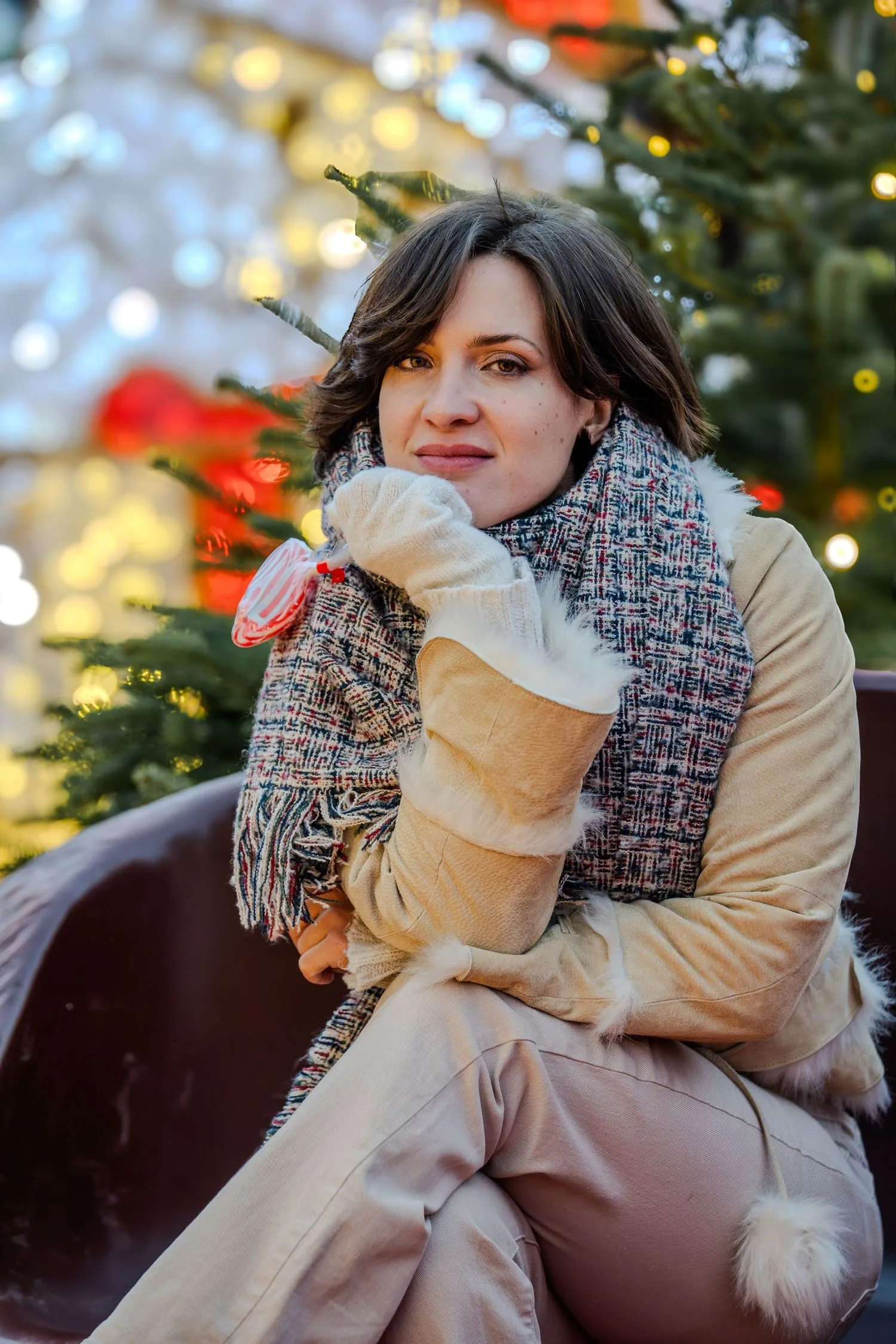 Portrait au marché de Noël : manteau en peau lainée et sucette à la main devant les guirlandes