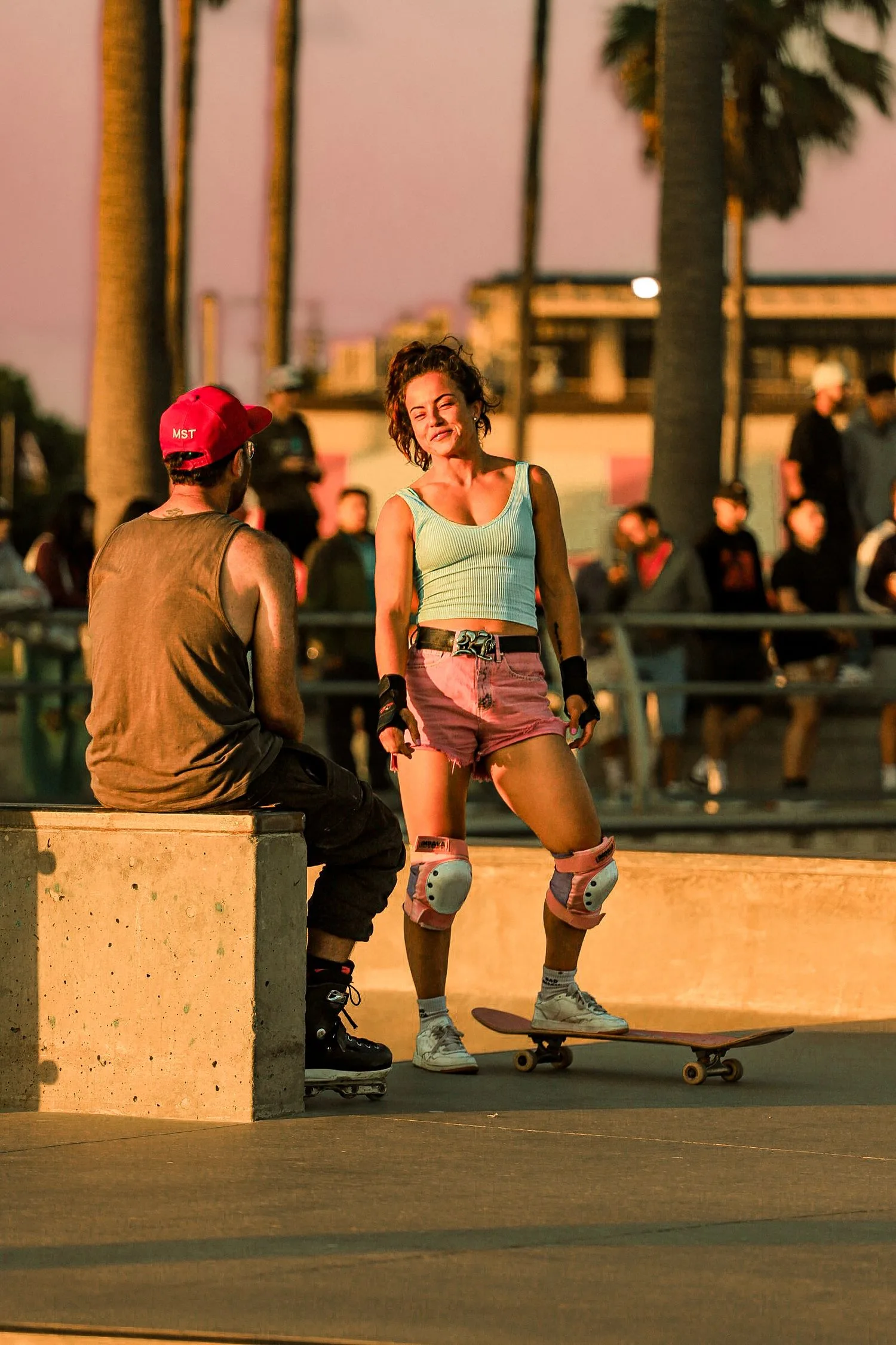 Fin de journée au skatepark : une skateuse discute avec un spectateur assis sur le muret