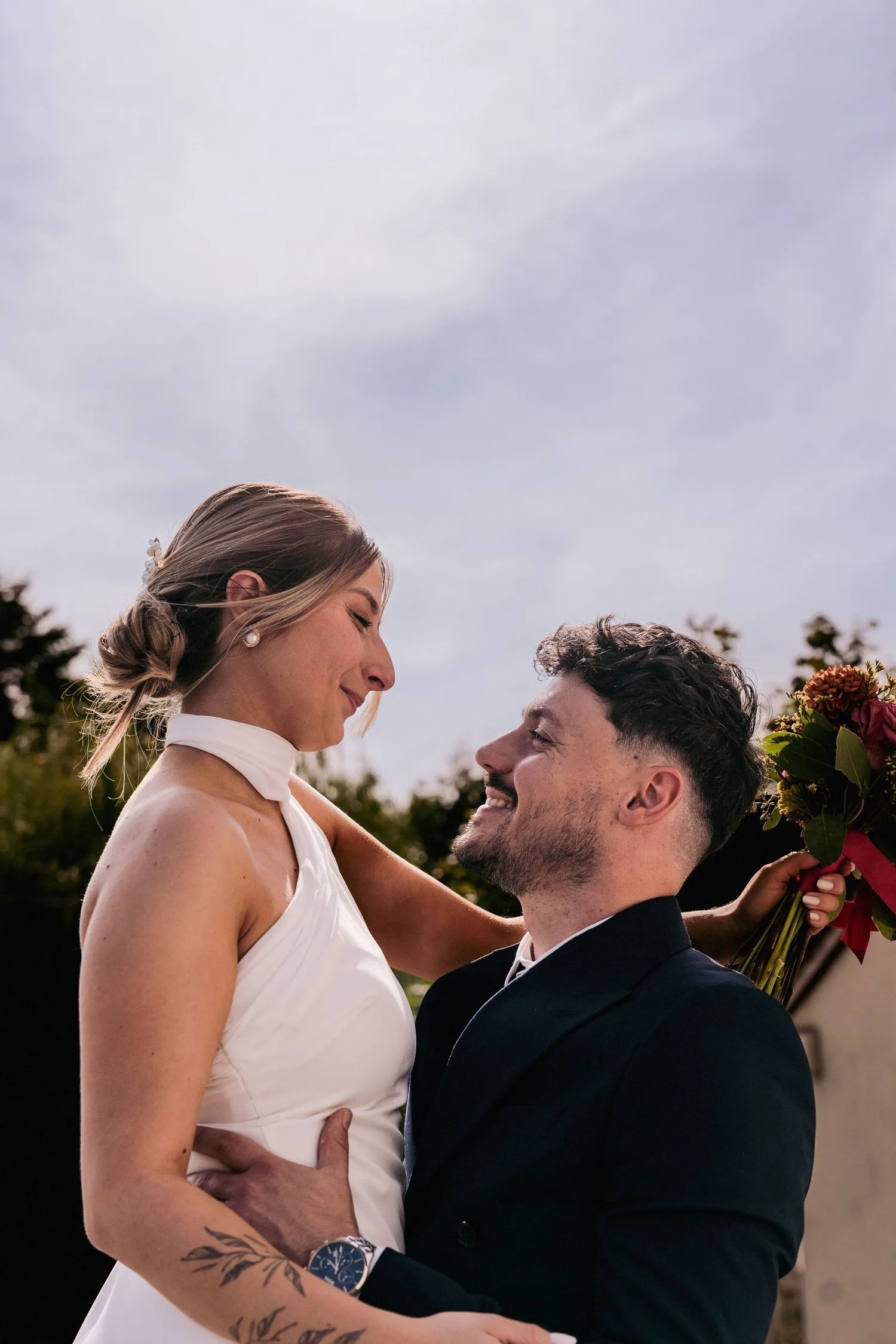 Les mariés enlacés, le marié riant, la mariée tenant son bouquet