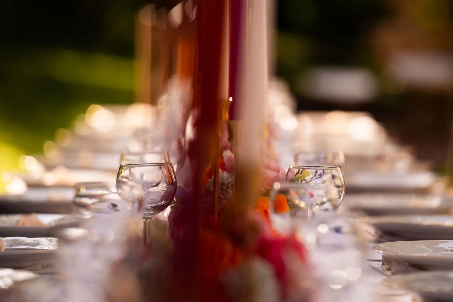 Table de réception en contre-jour, bougies et verres à vin dans la lumière dorée