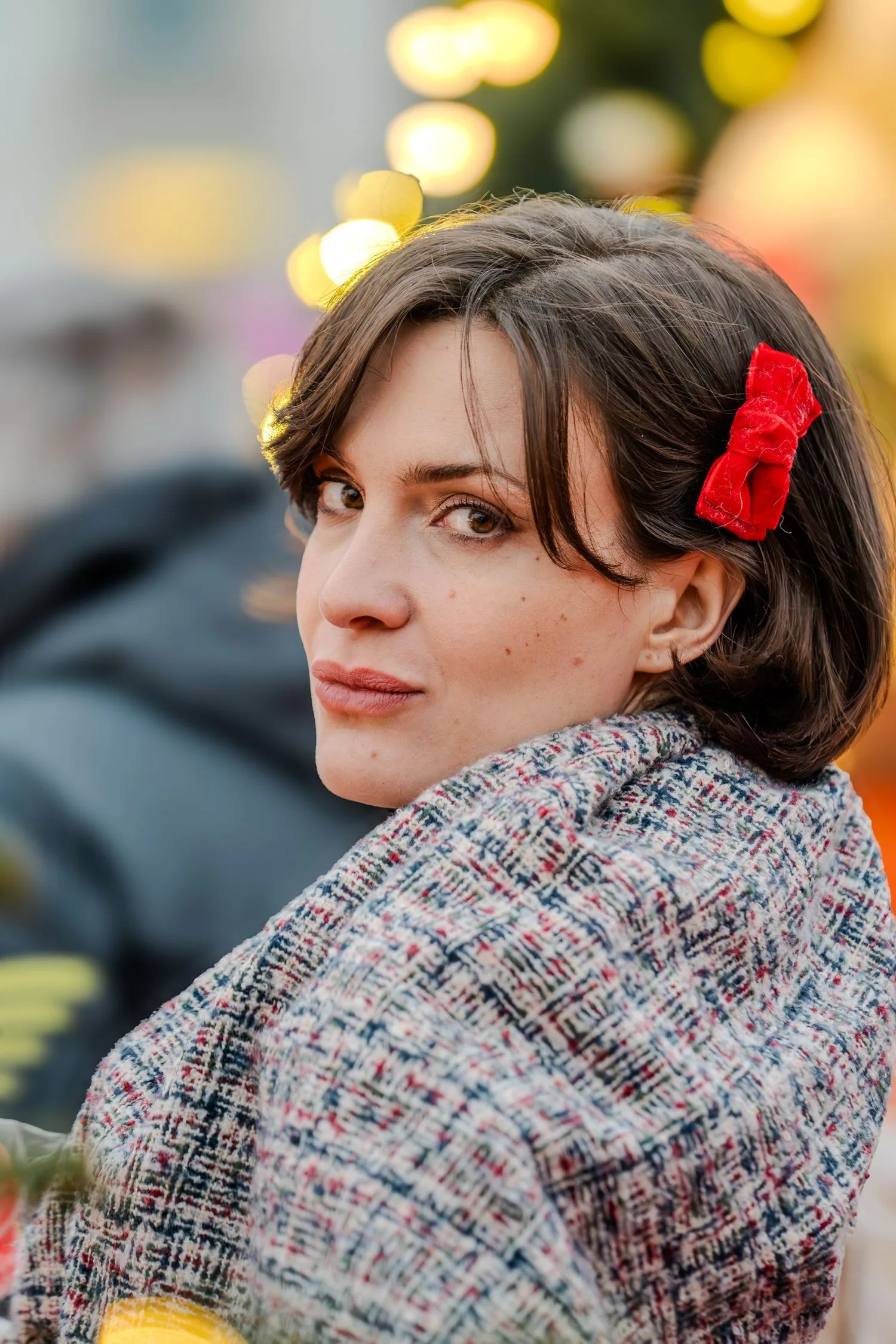 Portrait en extérieur : regard par-dessus l’épaule, barrette fleurie rouge et châle en tweed