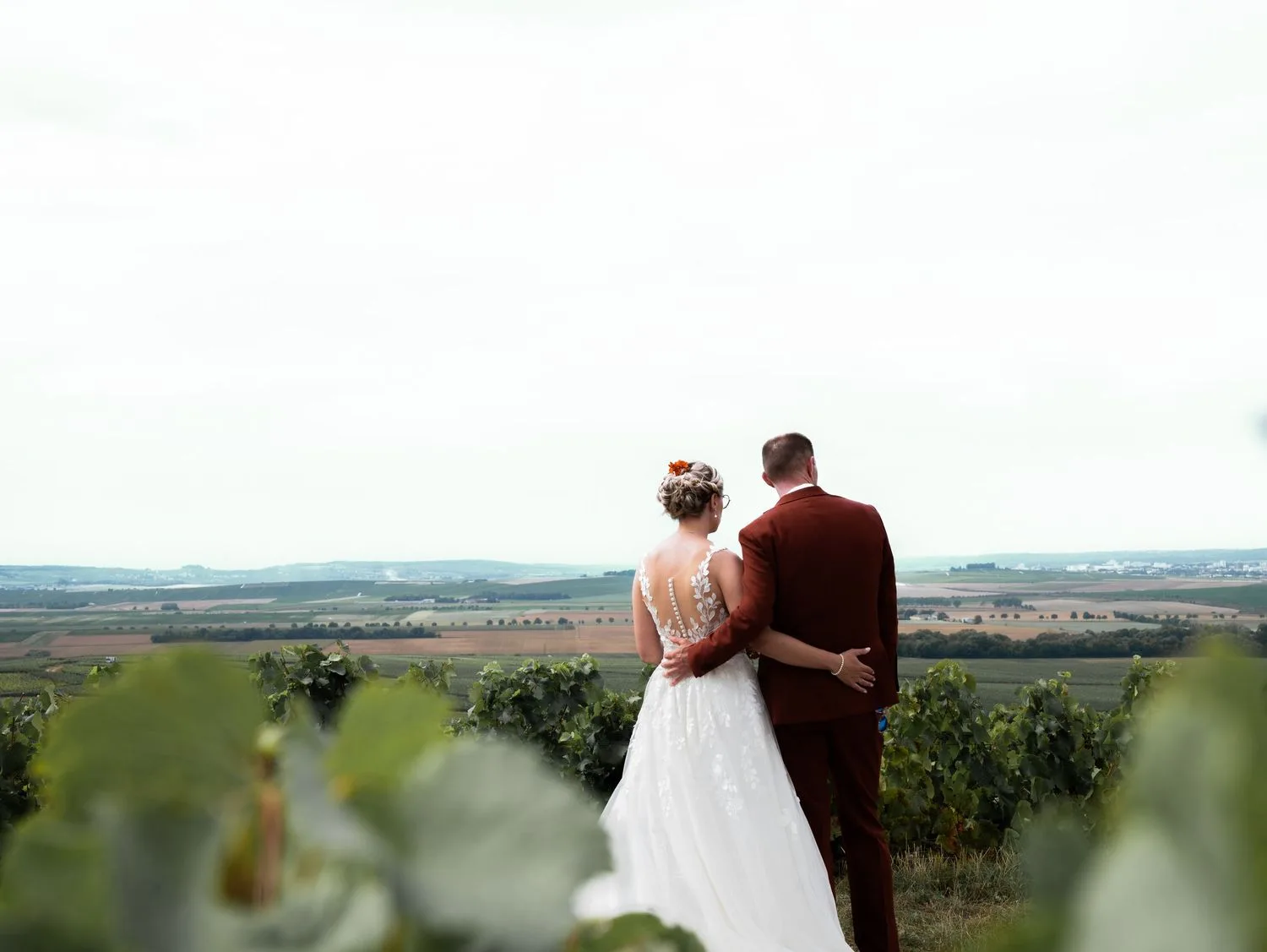 Les mariés de dos face aux vignes et à la campagne ouverte