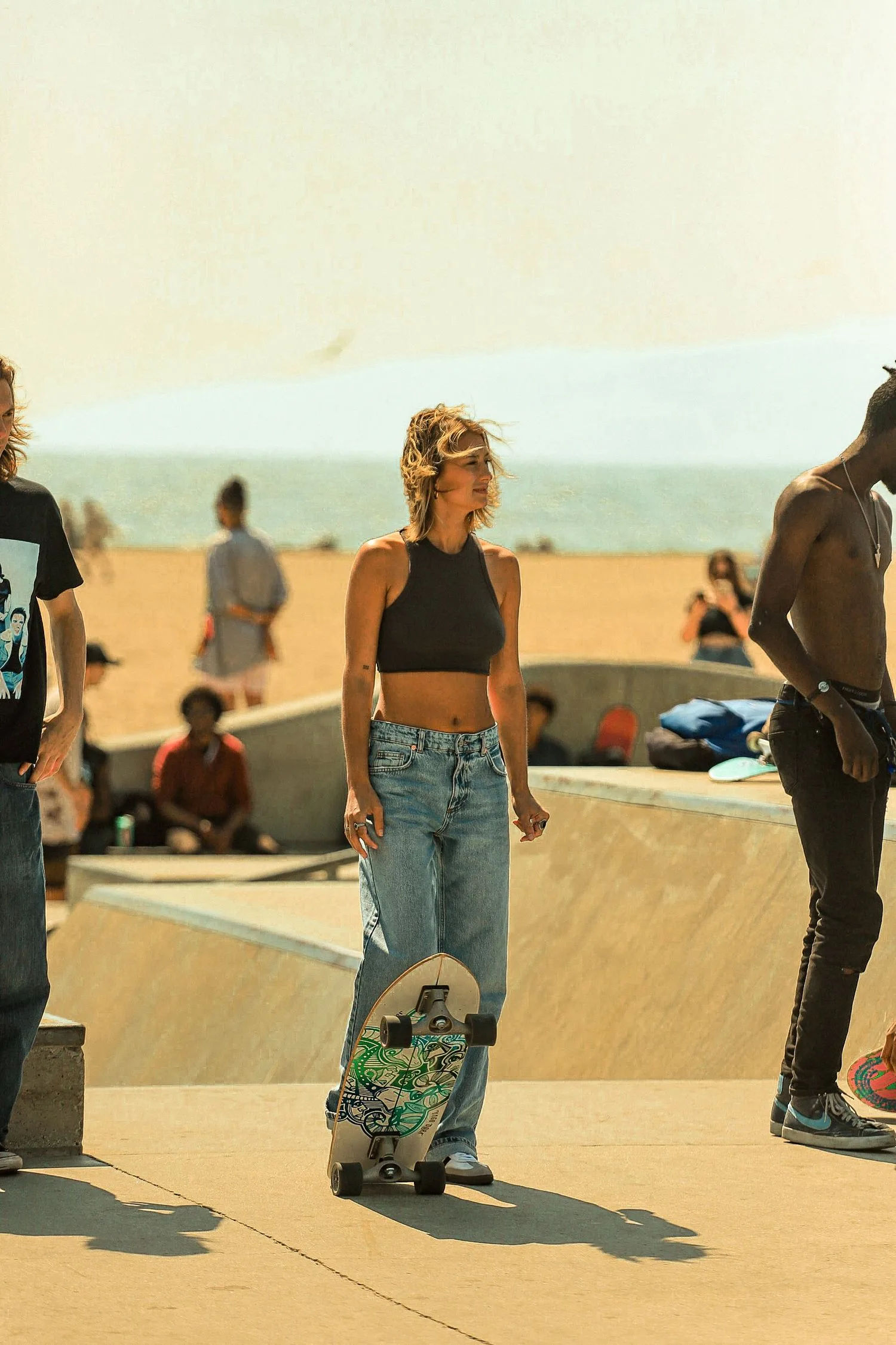 Skateuse debout avec sa planche, l’océan en arrière-plan
