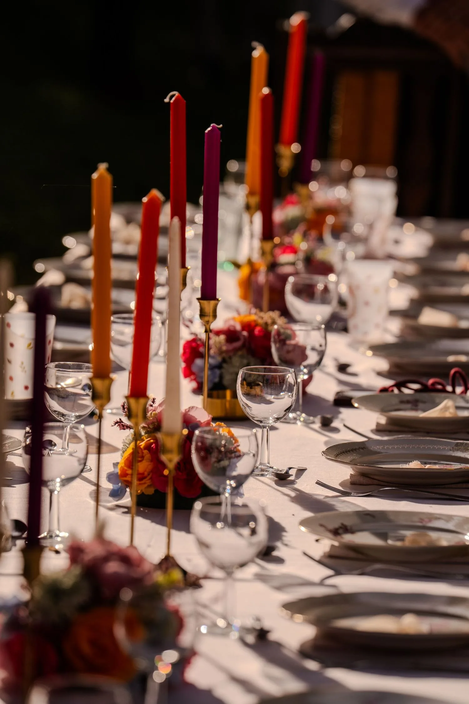 Table de réception dressée, bougies colorées dans des bougeoirs dorés et fleurs