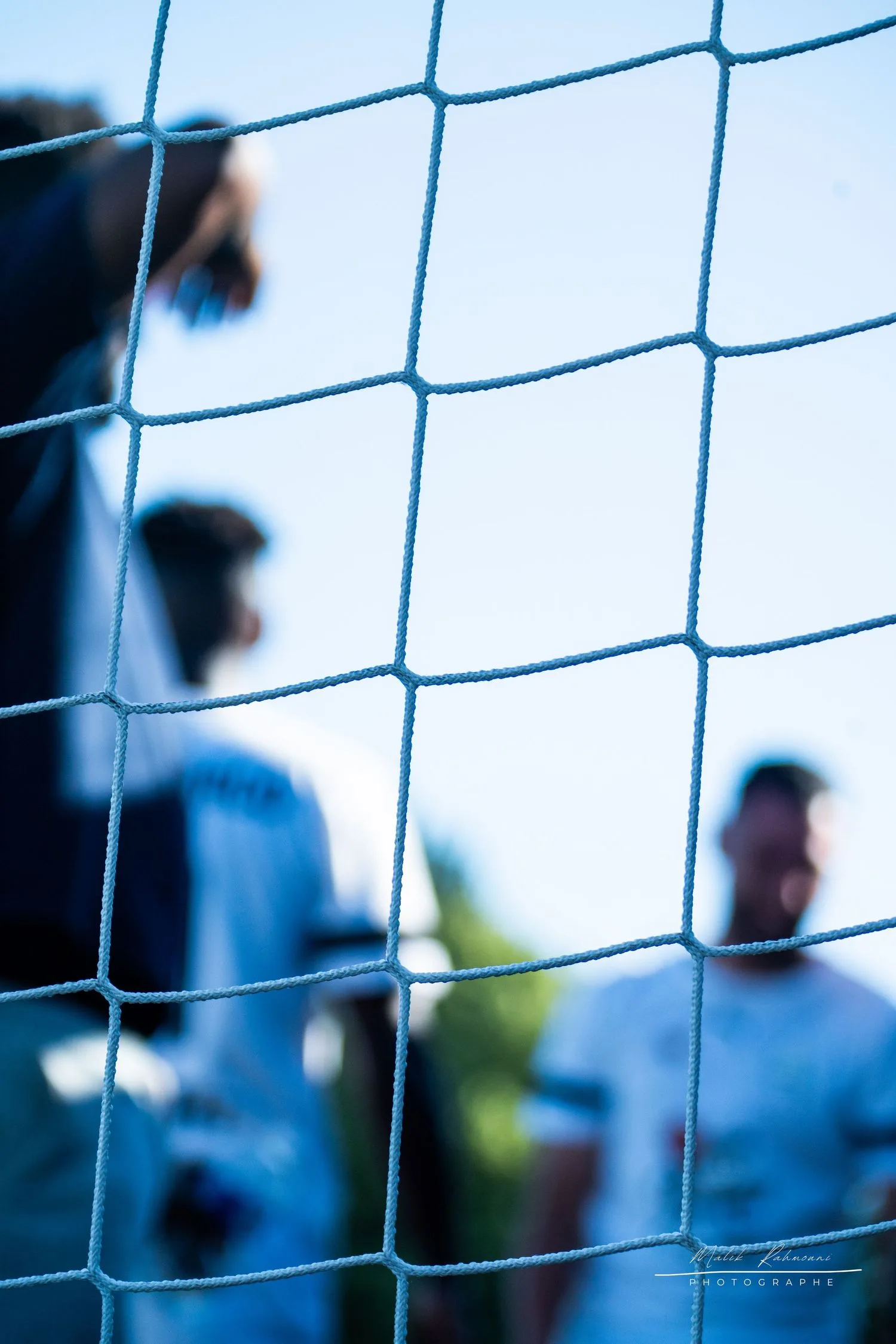 Joueurs aperçus à travers les mailles d’un filet, lors d’un match en extérieur