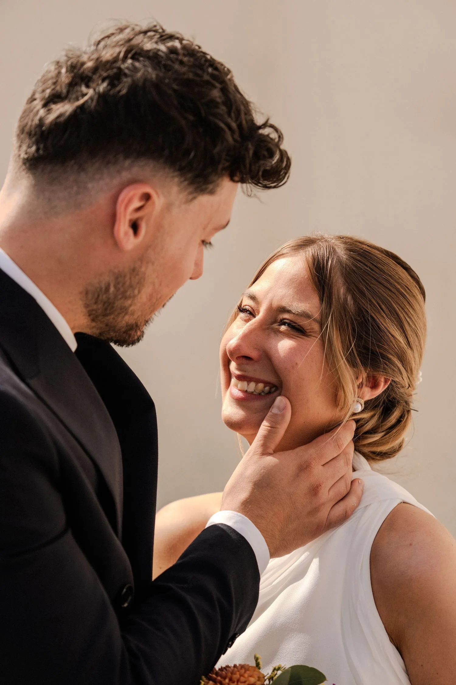 Le marié prend le visage de la mariée entre ses mains, elle éclate de rire