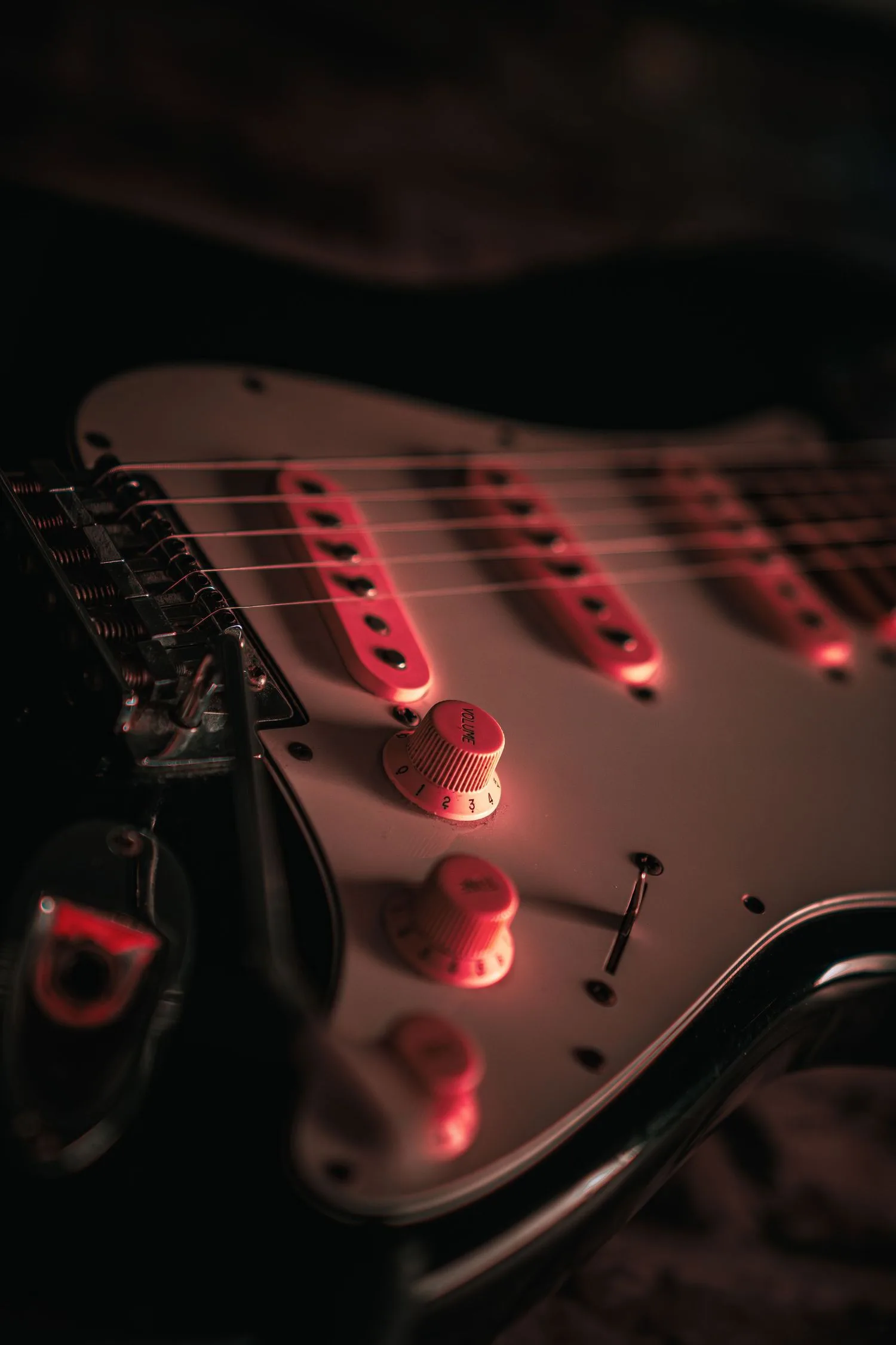 Gros plan sur une guitare électrique éclairée de rouge pendant un concert
